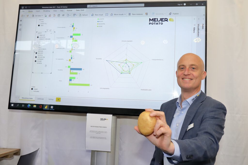 Commercial director Johan van der Stee of Meijer Potato holding a potato in front of the digital robustness index at the Potato Variety Days 2021.